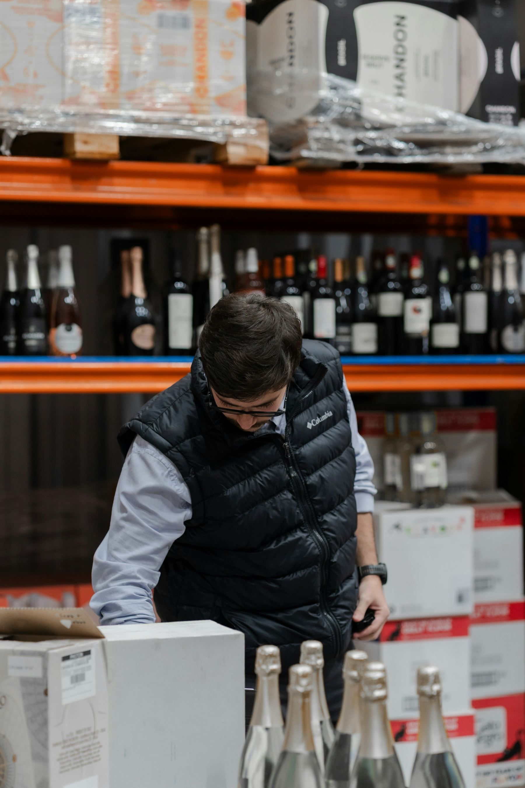 A warehouse worker checking cases of drinks beside the racking