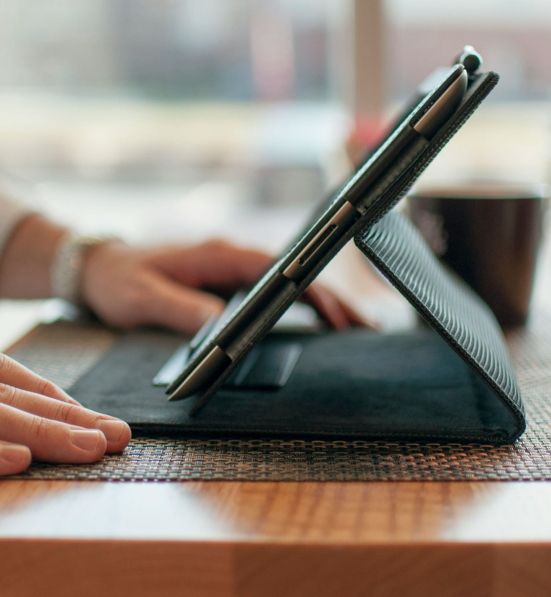 Hands working on a tablet propped up on an office desk