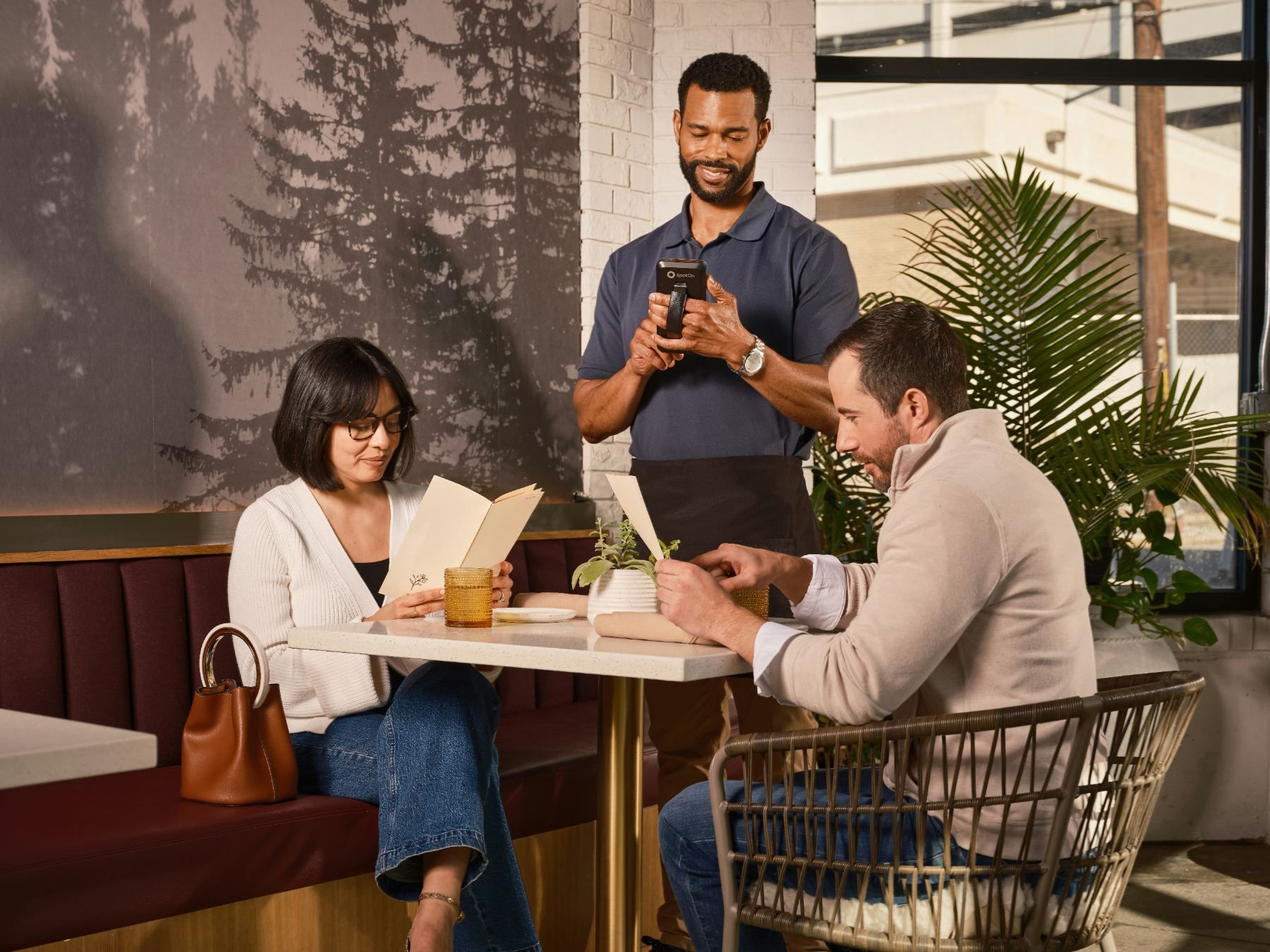 A waiter taking an order on a handheld terminal at a restaurant table